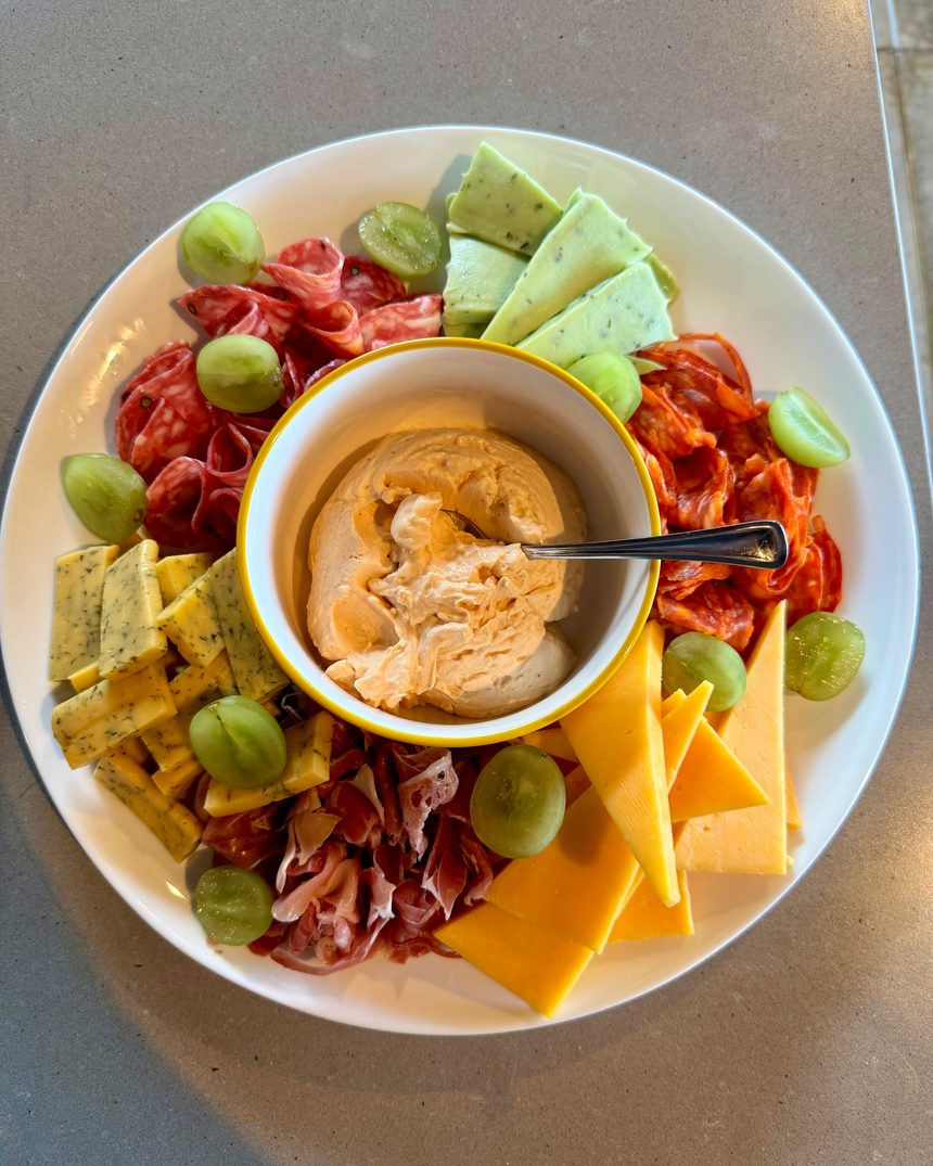 A charcuterie and cheese board with grapes and a dip, set out for guests in a villa in Guanacaste